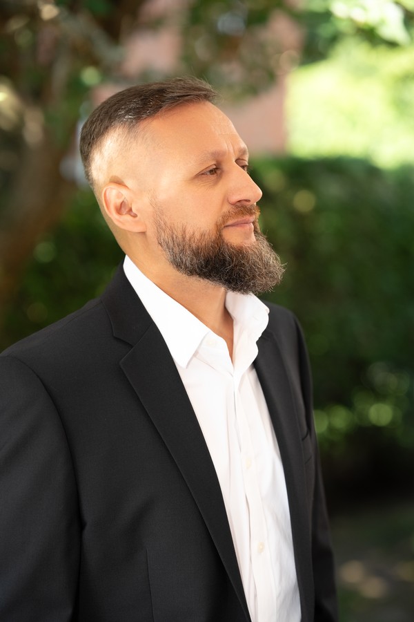The groom in a black suit, looking toward the light