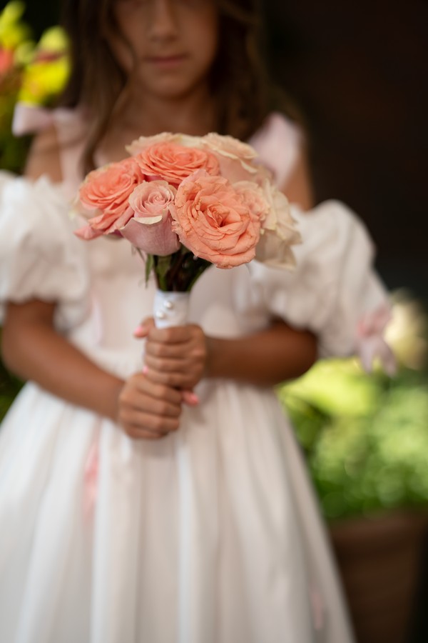 A small bouquet of peach roses held by a flower girl
