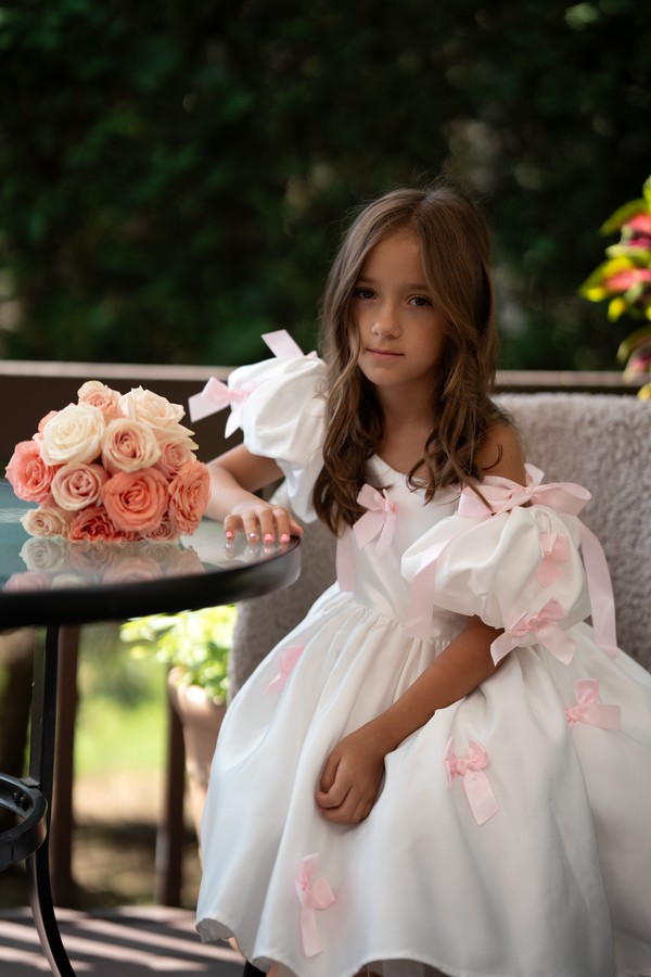 A flower girl seated beside her peach rose bouquet