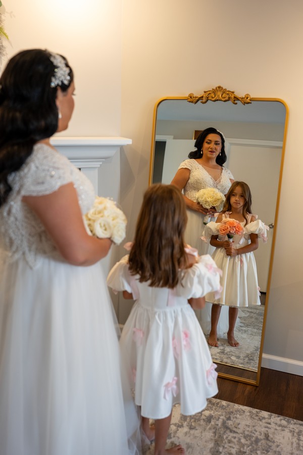 The bride and a flower girl reflected in a mirror