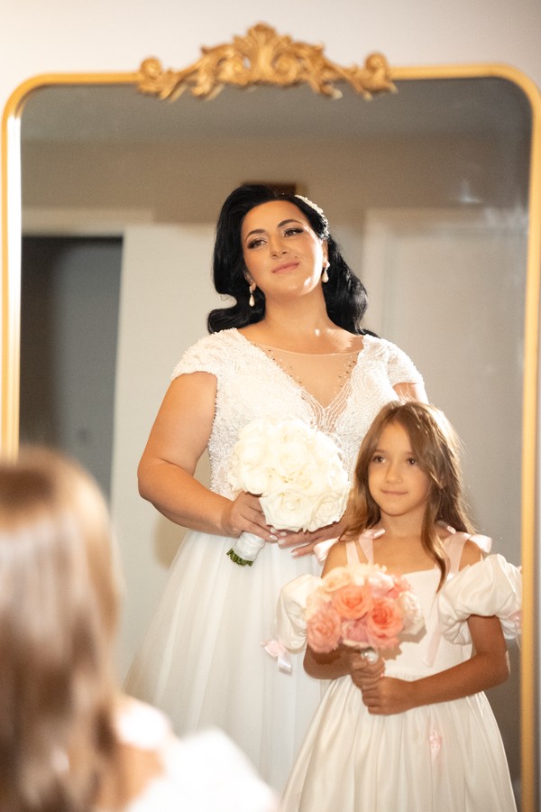 The bride and a flower girl sharing a quiet moment at the mirror