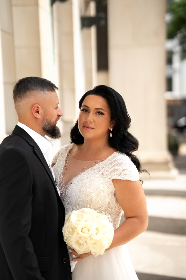 The newlyweds together beside pale stone columns