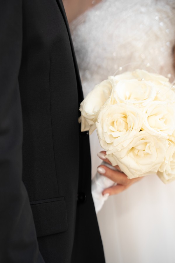White roses against the bride’s gown and the groom’s suit