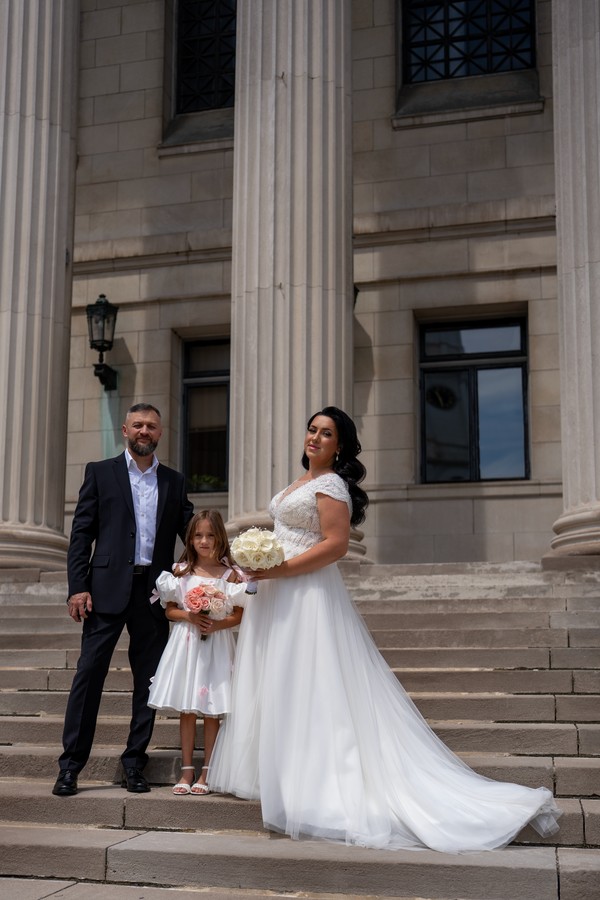 The couple and a flower girl on the stone steps