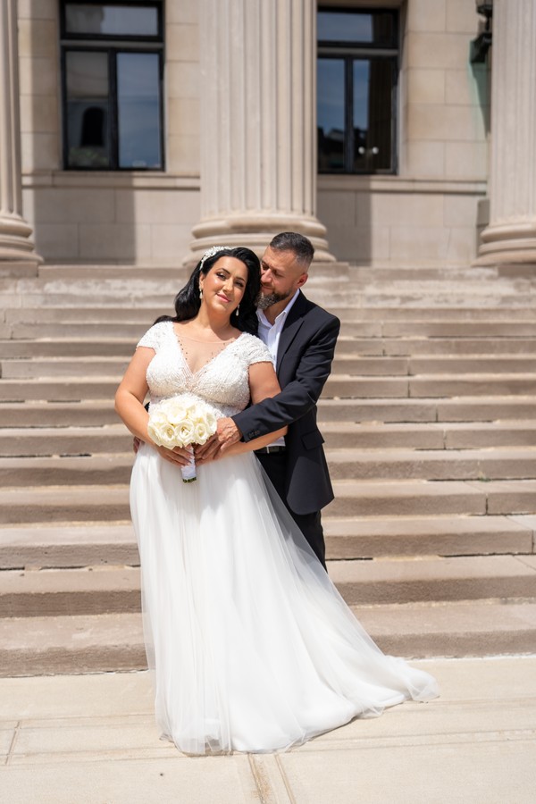The couple embracing on the steps beneath tall columns