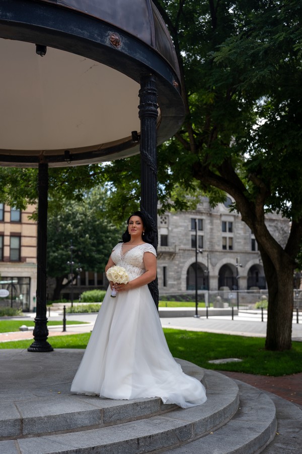A full-length bridal portrait beside a garden pavilion