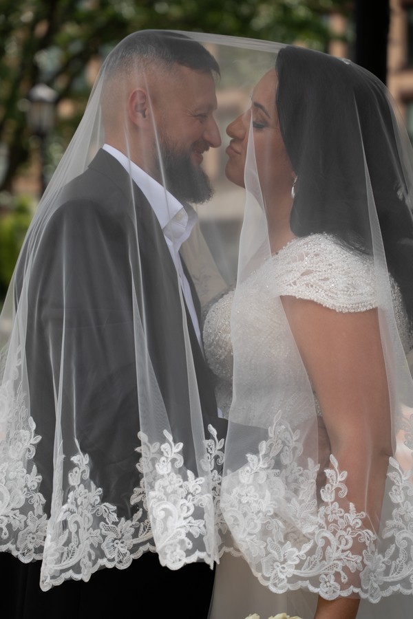 The newlyweds face to face beneath the lace veil