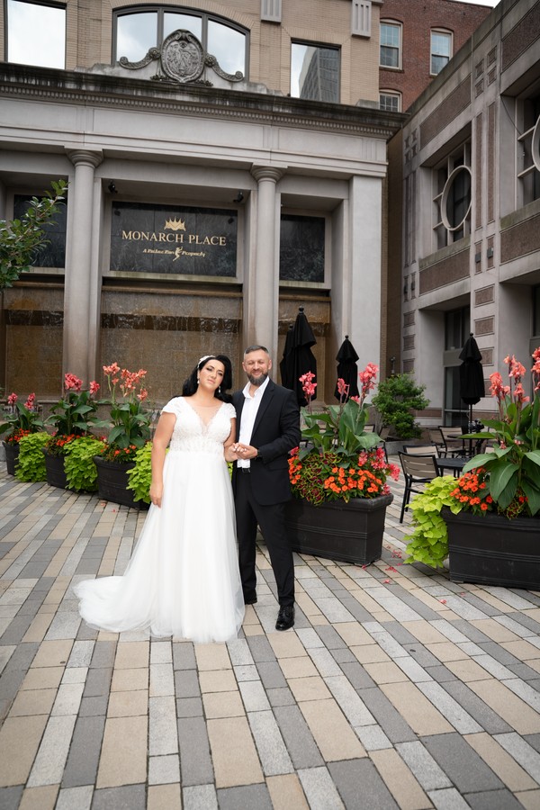 The couple beside the flowers in a stone courtyard