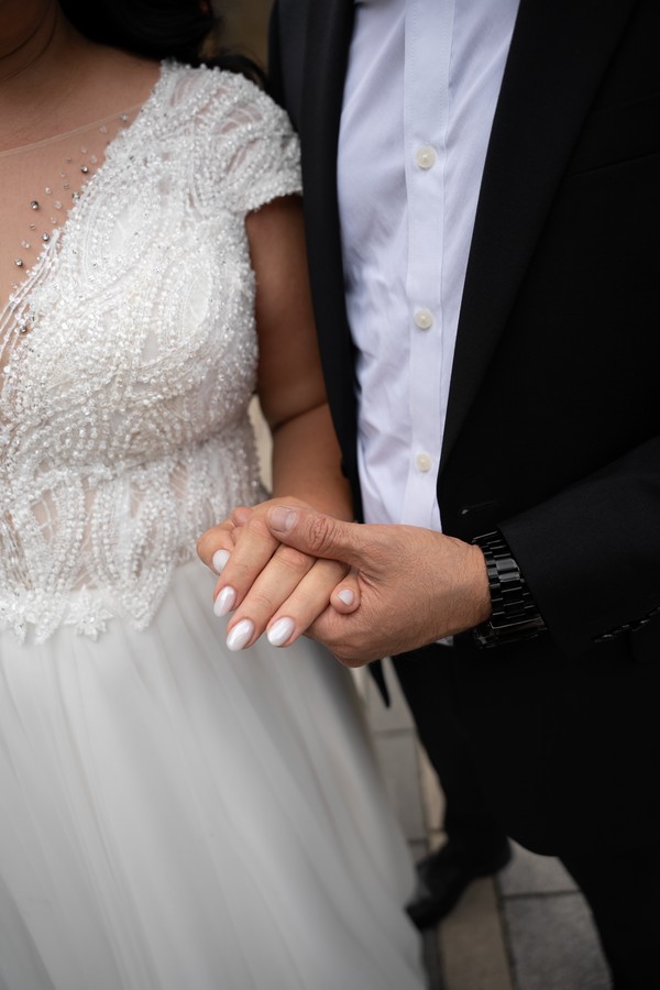 The bride’s ring and lace gown beside the groom’s suit