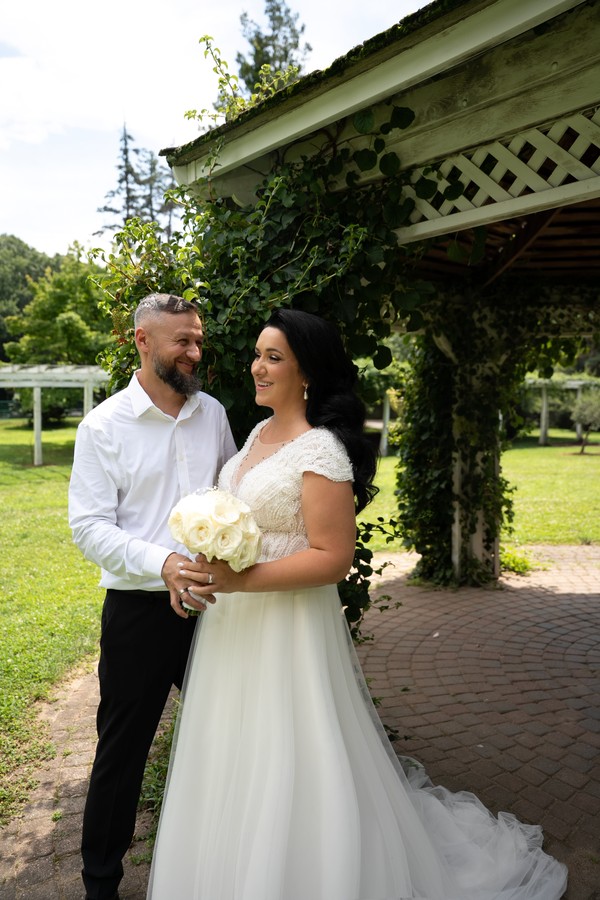 The bride and groom smiling beneath the arbor