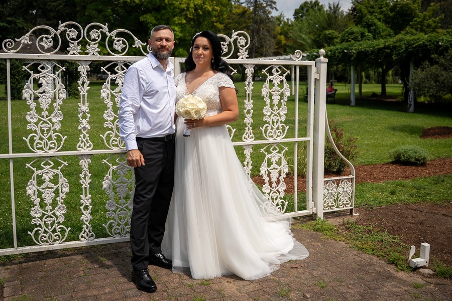 The newlyweds beside an ornate white garden gate