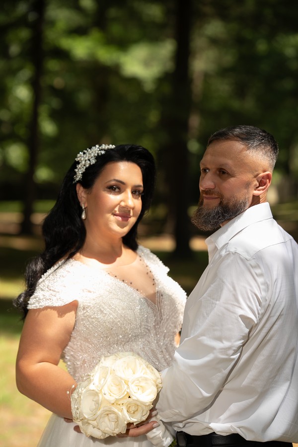 The bride and groom with a bouquet of white roses