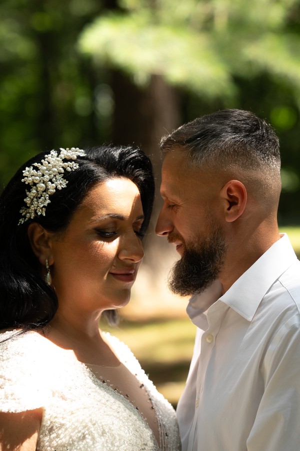 The couple leaning close in the dappled garden light