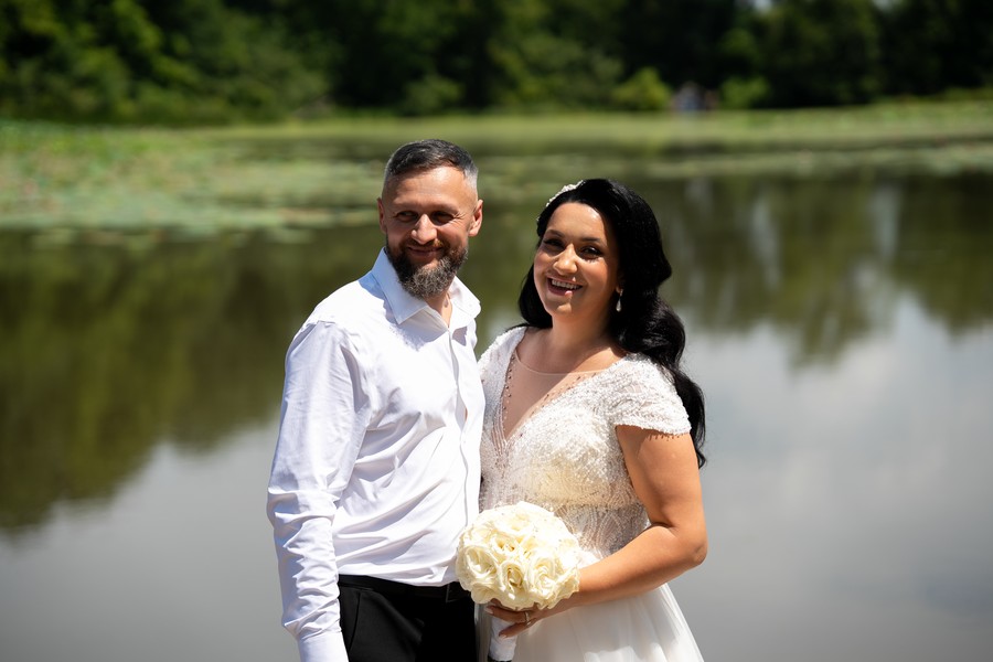 The newlyweds smiling beside the pond