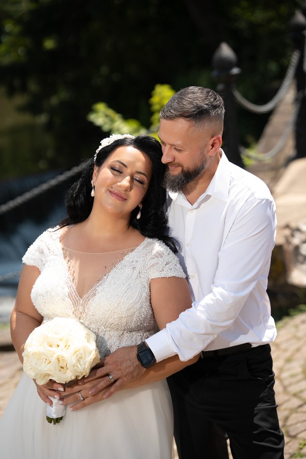 The groom embracing the bride beside the water