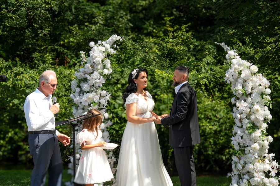 The bride and groom exchanging vows beneath the flowers