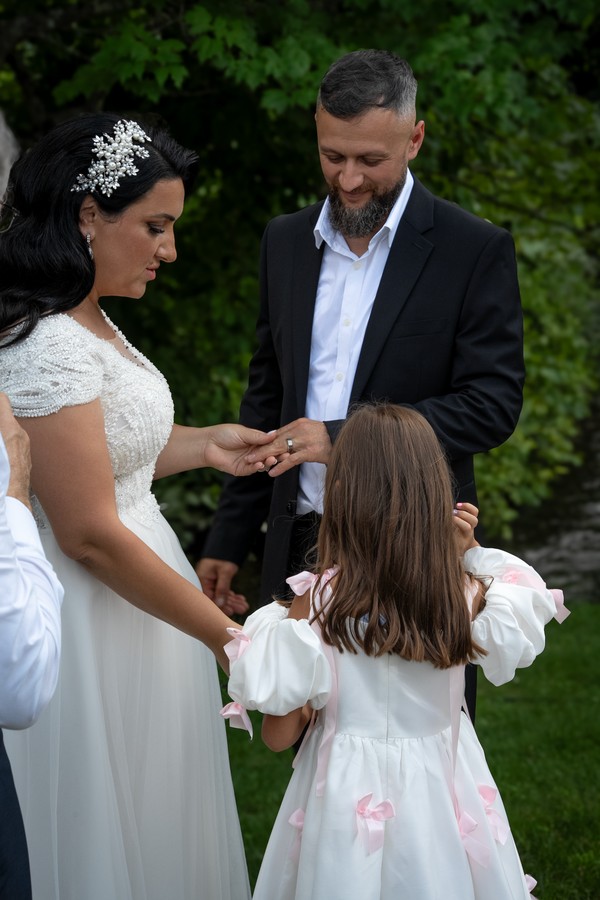 The newlyweds exchanging rings with a flower girl beside them