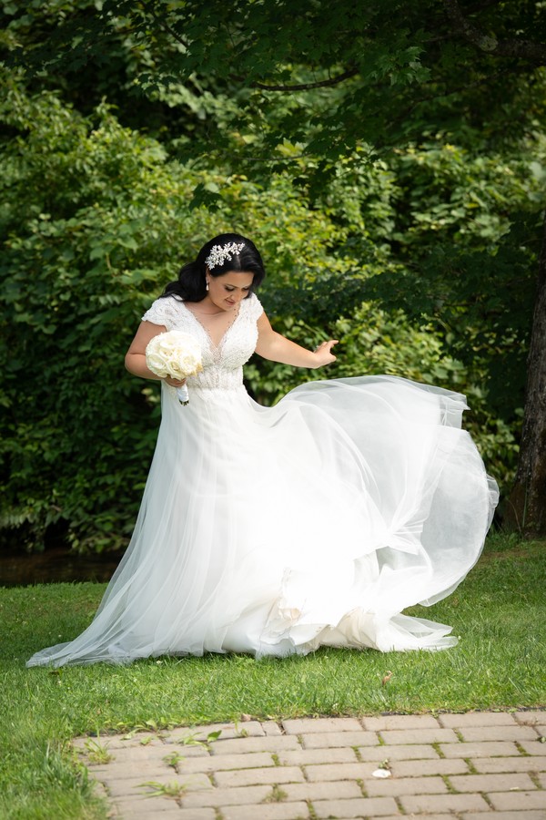 The bride holding out her gown in the garden