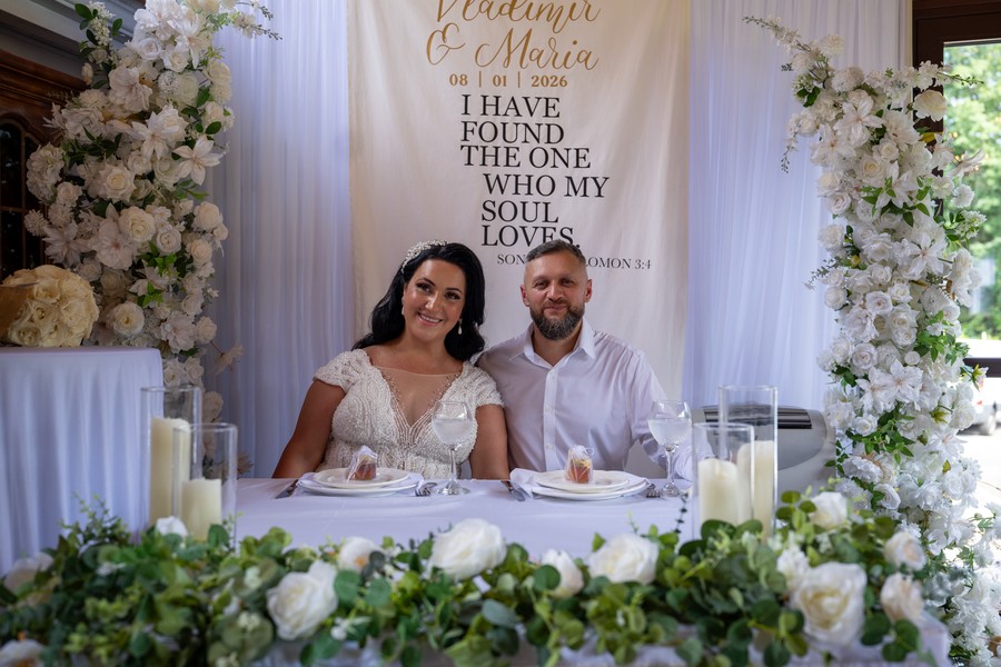 Vladimir and Maria seated at their flower-filled wedding table
